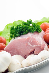 Raw pork on the plate with tomatoes,garlic and mushrooms