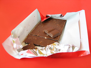 chocolate bar in paper and foil cover on red
