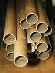 Cardboard tubes stacked on a shelf in a warehouse.