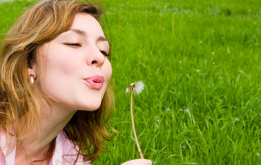 young girl blowing on the dandelion
