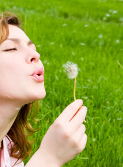 young girl blowing on the dandelion