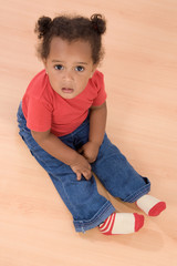 Naklejka premium Adorable african baby sit over wooden floor