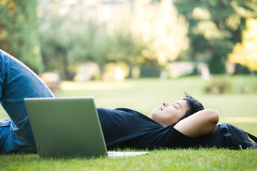 An asian college student lying down on the grass
