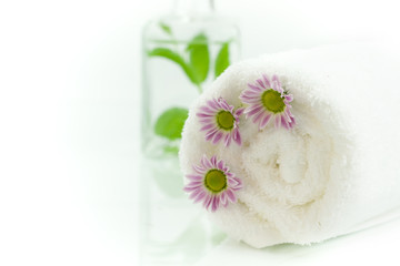 Towel, flowers and jar with fresh leaves