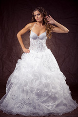 Fashion model wearing wedding dress at brown studio background