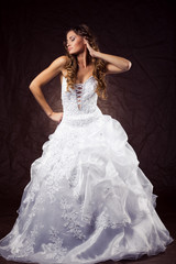 Fashion model wearing wedding dress at brown studio background