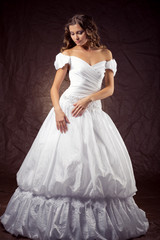 Fashion model wearing wedding dress at brown studio background