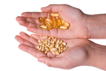 Fototapeta premium Hands weighting pine nuts and fish oil capsules