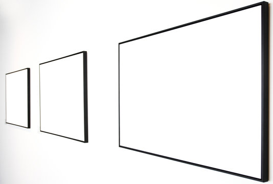 Three empty frames on white wall in museum