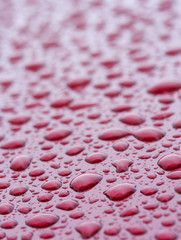 a picture of water drops on a red metal surface
