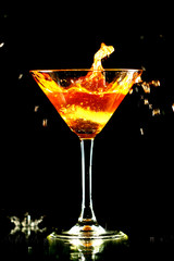 alcohol splash in martini glass on black background
