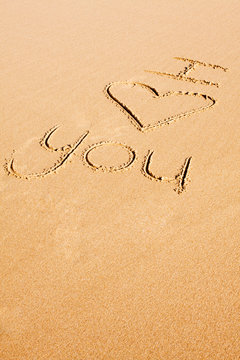 The words "I love you" written on the beach sand