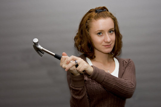 portrait of a beautiful redhaired girl holding a hammer