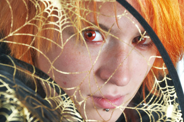 red-hair witch looking through golden spider's web