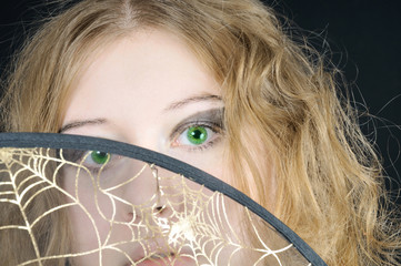 Pretty curly green-eyed girl looks atop the web-hat