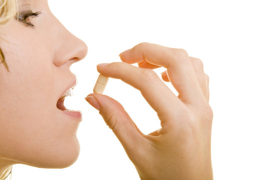 Blonde Frau hält eine Tablette vor ihrem Mund