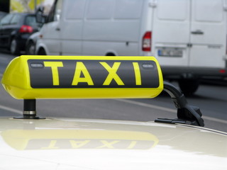 Naklejka premium Enseigne Taxi jaune et noire sur le toit d'une voiture.