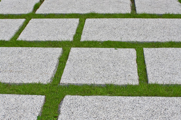 Path from the granite plates on a green grass