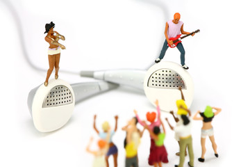 Miniature band standing on a pair of ear buds. MP3 concept.