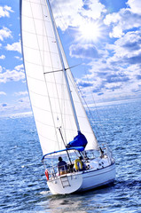 Sailboat with white sail sailing on a sunny day