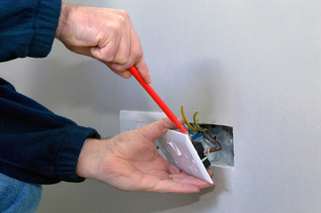 The hands of an electrician installing a power socket - 10135234