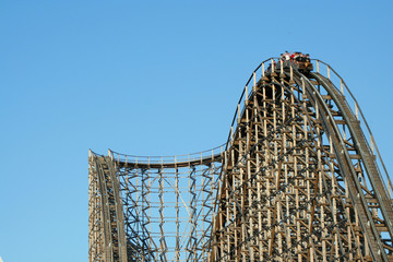 Wooden roller coaster support beams against blue sky