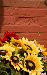 A spring bouquet with sunflowers in front of a brick wall