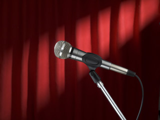 A microphone on stage over a red background.