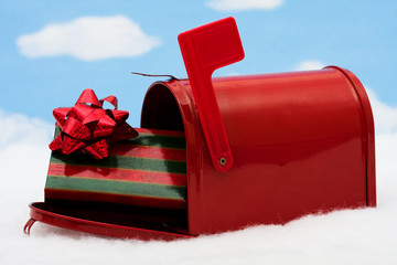 Red mailbox filled with presents and the flag up sitting on snow