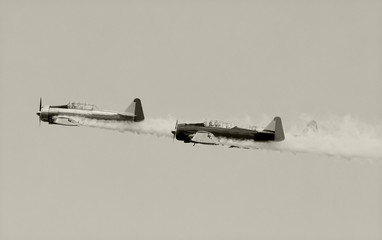 Three vintage airplanes with smoke trail