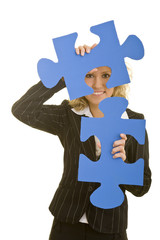 Blonde Frau schaut durch zwei große blaue Puzzleteile