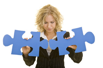 Blonde Frau im Jackett verbindet zwei große blaue Puzzleteile