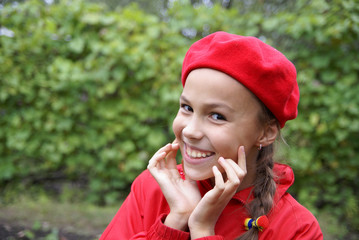 Cheerful preteen in red girl clasping hands on green background