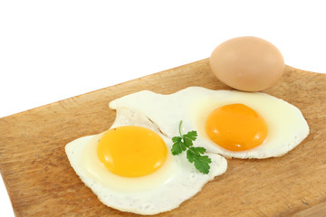 fresh and fried eggs on wooden plate