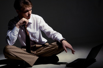 Fototapeta premium Man seated inside dark room in front of laptop