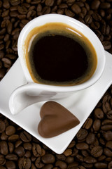 Cup of espresso with heart shaped chocolate candy