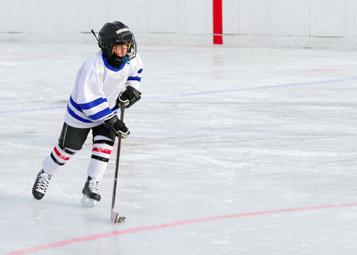 A young hockey player races with the puck.
