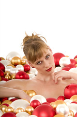 Fototapeta na wymiar Sexy young woman sunken in Christmas balls on white background