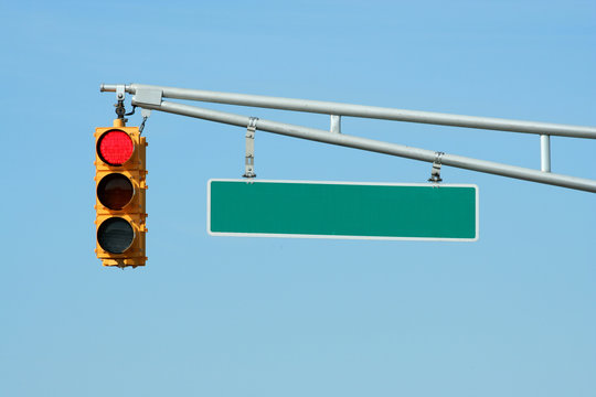 Red traffic signal light with sign on blue sky