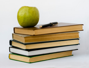 Pile of books, pen,  and apple isolated on white background
