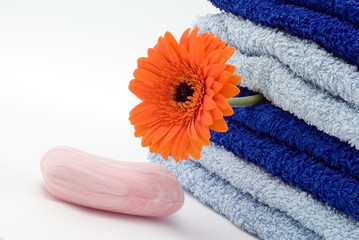 Fototapeta na wymiar Blue towels, soap and flower on the white background
