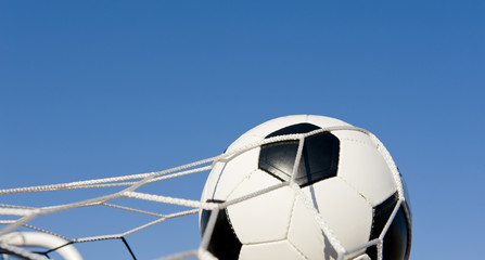 A traditional soccer ball or football in a goal net