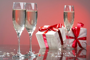 Glasses of champagne, gifts with red tapes and bows