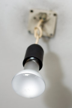 Light bulb on cable hanging from ceiling
