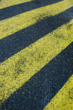 yellow hatched stripes on asphalt, symbolic of a no-go area