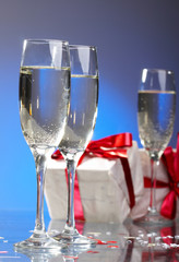 Glasses of champagne, gifts with red tapes and bows