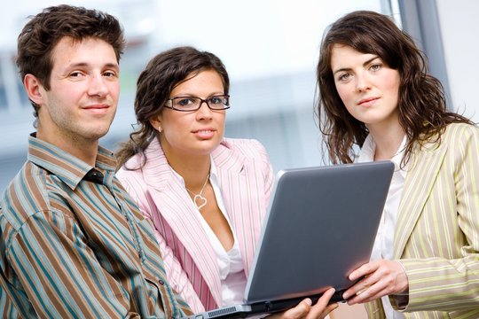 Happy businesspeople teamworking on laptop