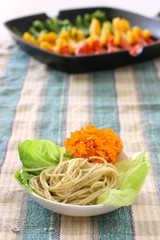 Pasta olio with edible flower and lettuce in small bowl