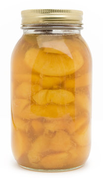 Homemade jar of sliced, canned peaches on white background.