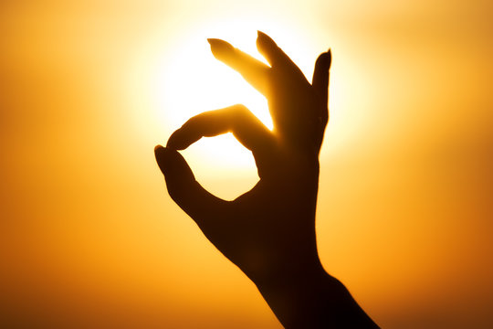 Ok hand sign silhouette. On bright sun background.